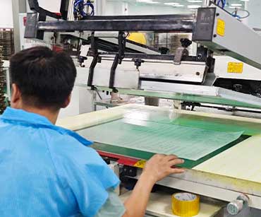 Worker reviewing printed sheets at a production station